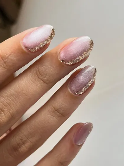 A detailed view of the minimal glittery nails, showing the delicate gold glitter line accenting the soft pink cat-eye polish.