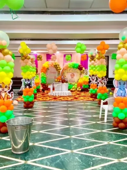 A wide view of a jungle-themed party in a banquet hall. The space is filled with balloon pillars featuring different animal cutouts, creating an immersive and fun environment for kids.