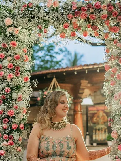 The bride posing on a swing decorated with an arch of pink and white roses.