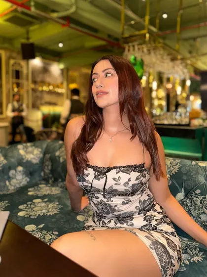 Sitting on a floral couch that matches the dress, a perfectly coordinated style moment.