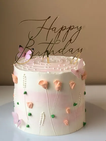 A simple and joyful cake with hand-piped peach-colored tulips and edible butterflies.