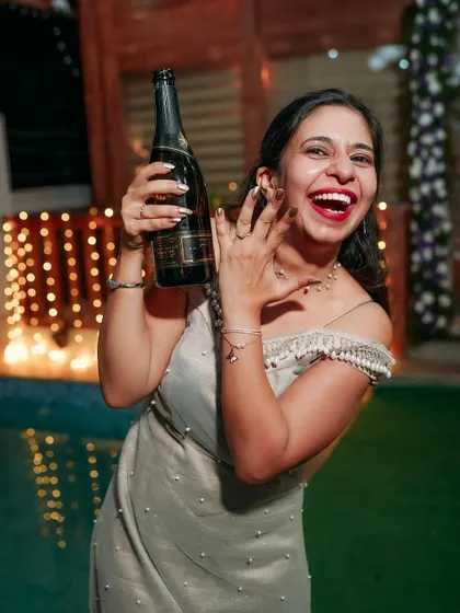 Popping the champagne to celebrate! A candid shot of the bride's exuberant happiness during the engagement party.