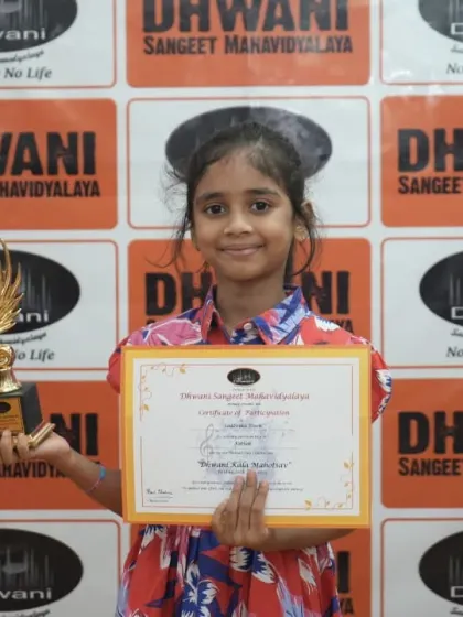 A young girl proudly holds her certificate and trophy.