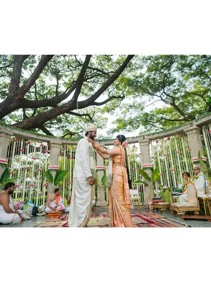 A candid moment during the wedding ceremony, where the decor serves as a beautiful, unobtrusive backdrop. The hanging floral strings of tuberose and pink nerium add a touch of delicate color to the scene.