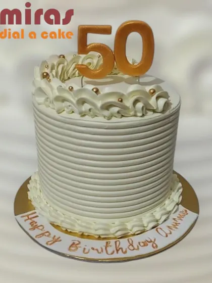 A classic and elegant cake for a 50th birthday. The tall, white-frosted cake is simply decorated with a golden "50" topper and piped swirls, proving that less can be more.