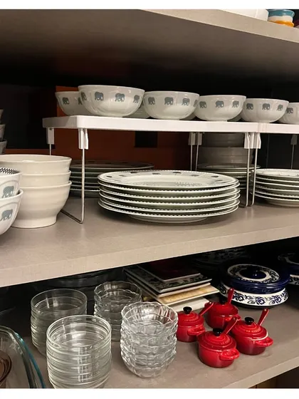 Here is another example of using a simple white riser to organize a dinner set. This method prevents you from having to lift heavy stacks of plates to get to the bowls underneath.