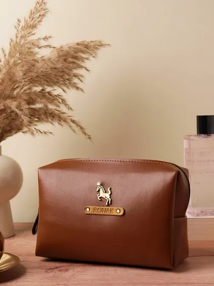 My personalized vegan leather pouch is a versatile accessory, perfect for storing toiletries, makeup, or tech gadgets. This one in tan is customized for "Ronak" with a horse charm.