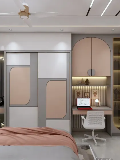 A close-up of the study and wardrobe area in a kids' room. The design is compact, functional, and uses a modern color palette of pink, grey, and white.