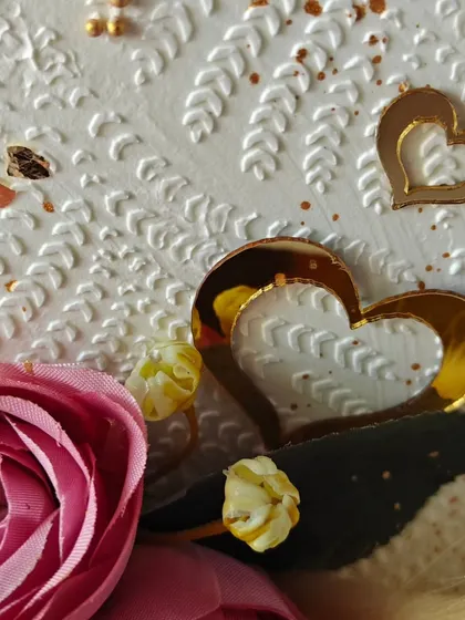 A close-up of the top-forward cake, showing the intricate stencil texture and the delicate gold hearts.