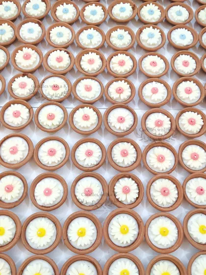 An overhead view of the 120 daisy clay pot candles, showing the variety of pastel colors chosen for the birthday party favors.