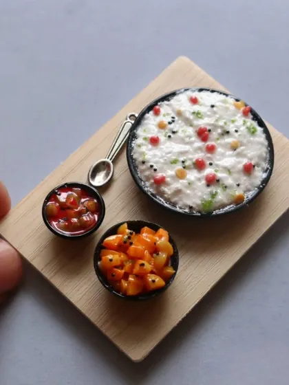 A miniature of curd rice served on a wooden board with two types of pickles.