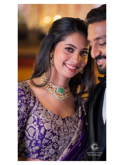 A happy, smiling portrait of Vidya and her partner. Her makeup is soft and radiant, enhancing her natural beauty and capturing the joy of the moment.