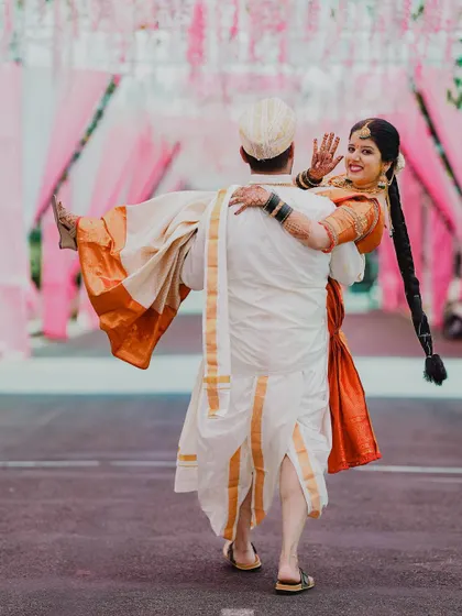 A fun and playful shot of the groom carrying the bride, her long braid swinging as he walks.