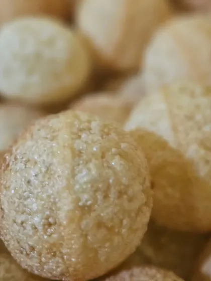 A close-up of a traditional Indian sweet, possibly Rava Ladoo, a delightful dessert option.