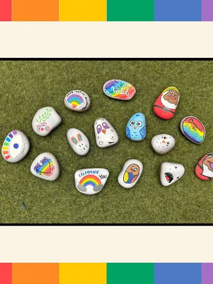 An overhead shot of the colorful and creative pebbles painted by employees during our Pride workshop. The variety of designs showcases individual expression within a unified theme.