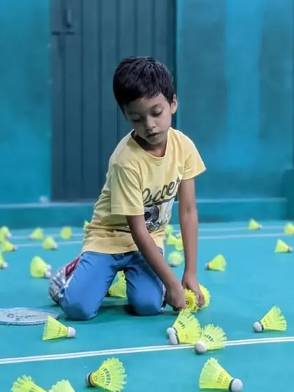 A young player carefully gathers shuttles, an important part of the post-drill routine.