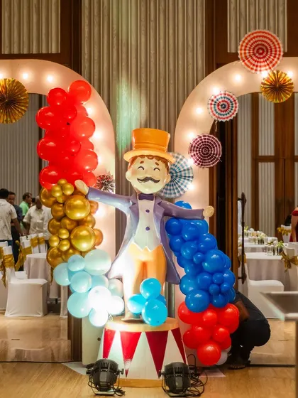 A grand entrance prop for a carnival party, featuring a welcoming ringmaster figure. The prop is surrounded by colorful balloons, setting a festive and exciting tone.