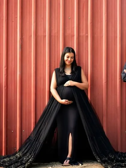 A bold and dramatic outdoor maternity portrait. The family dressed in black against a striking red industrial wall creates a modern and powerful image of strength and unity.