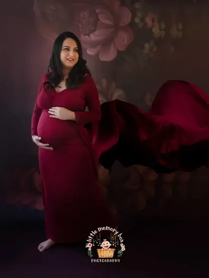 This portrait combines a rich, dark floral backdrop with a flowing red gown for a truly artistic and romantic feel. The fabric toss adds a sense of movement and grace.