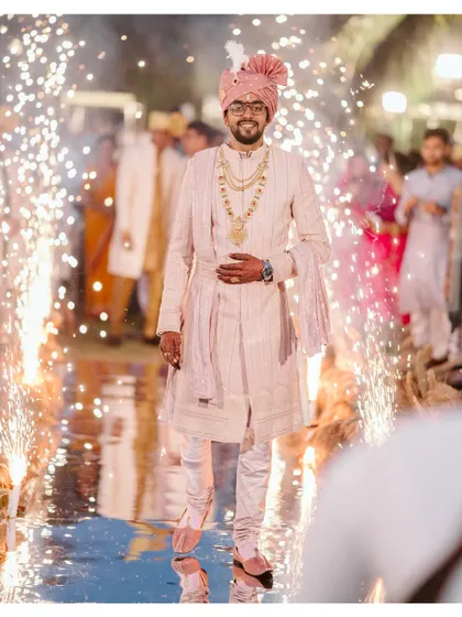 The groom makes a grand entrance, walking through a path of sparklers, looking regal in his wedding attire.