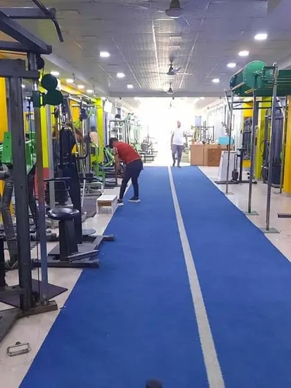 A full view of our training floor. You can see the long turf track for sprints and sled work, with various strength stations and free weight areas alongside it. There is space for everyone to focus on their workout.