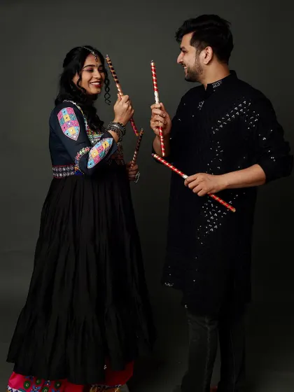 A festive Garba-themed maternity shoot! This playful photo with dandiya sticks celebrates culture, love, and the joyful anticipation of a new arrival.