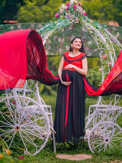A truly royal portrait for a mom-to-be. The red and black flowing gown creates a dramatic effect as it catches the wind, set against the whimsical white carriage prop for a perfect fairy tale maternity shoot.