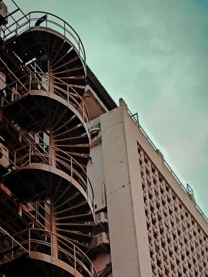 Another angle of the spiral staircase, showing its relationship with the adjacent building's textured facade.