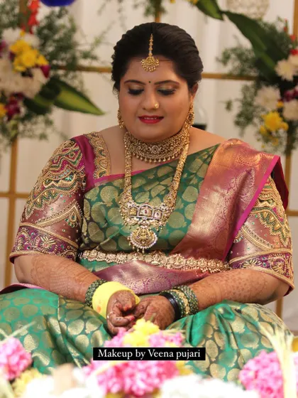 Rakshitha's radiant muhoortham look. The makeup highlights her features with a classic smoky eye and bold lip, perfectly matching her grand green and purple silk saree.