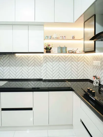 A wider view of the white kitchen, showing the ample storage provided by the floor-to-ceiling cabinets. The under-cabinet lighting illuminates the workspace, enhancing both functionality and ambiance.
