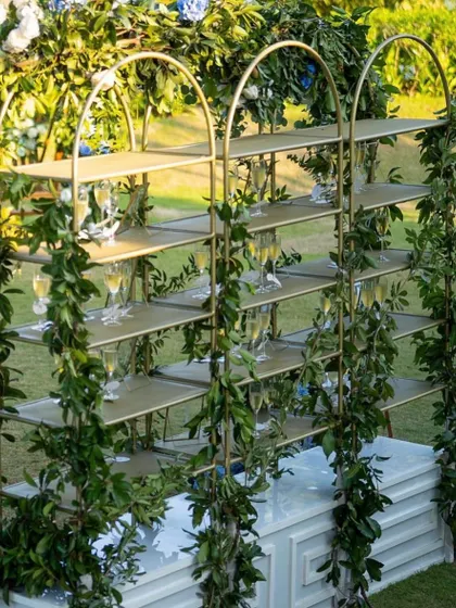 A creative champagne or welcome drink display shelf. Draped in greenery, this is a stylish and functional piece for any cocktail hour.