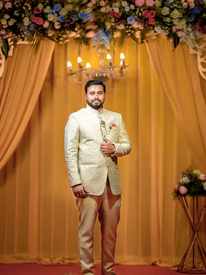 A stylish groom posing in his bandhgala jacket against an elegant draped backdrop.
