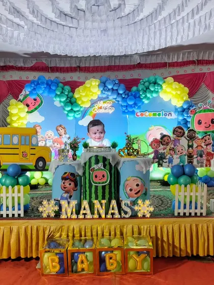 This Cocomelon theme includes a large school bus prop and a custom backdrop featuring the birthday boy's photo.
