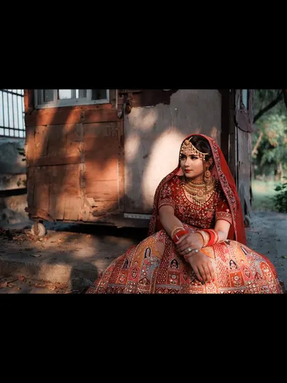 A wide-angle portrait of the bride seated in a rustic, outdoor setting. The dramatic lighting and composition create a powerful and artistic image.
