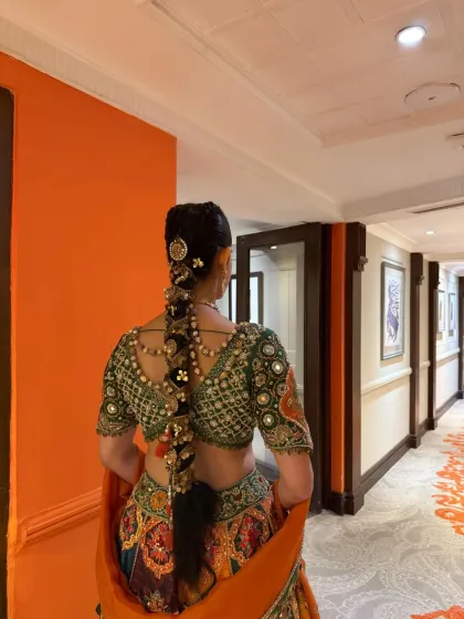 The bride walking down a hallway, showing how a long, traditional braid moves and complements the entire bridal ensemble. The hairstyle is both a statement piece and a functional part of the look.