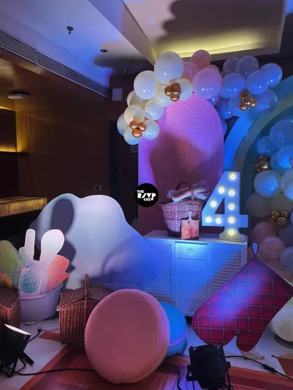 A close-up of the baking party decor, including a lit-up number '4', picnic baskets, and oversized props like an oven mitt and a pink macaron.