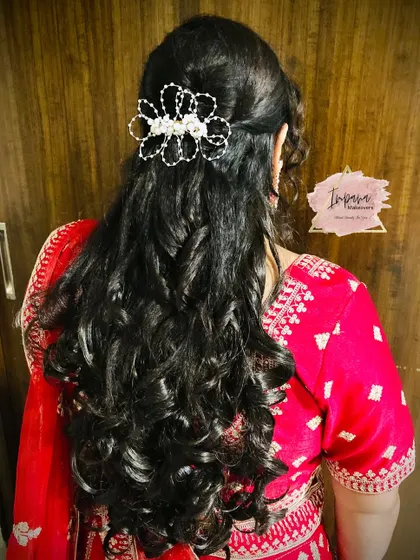 A half-up hairstyle with soft curls, perfect for a reception. A sparkling hair accessory adds a touch of glamour to this romantic look.
