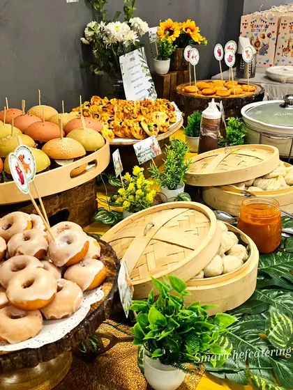 A beautifully arranged grazing table for a Lion King-themed birthday party. The spread includes mini pizzas, sliders, donuts, and steamed momos, offering something for everyone.