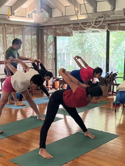A class practices Prasarita Padottanasana (Wide Legged Standing Forward Bend). This pose is excellent for stretching the hamstrings and spine, and this image shows the uniformity and focus of the group.