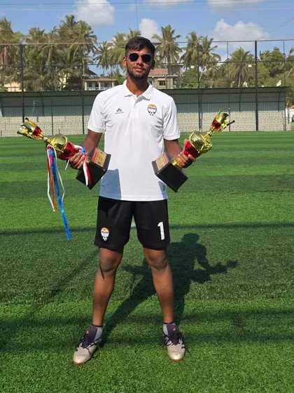Coach Jisto Francis holding two trophies. Our coaching staff is accomplished and brings a wealth of experience to the academy.