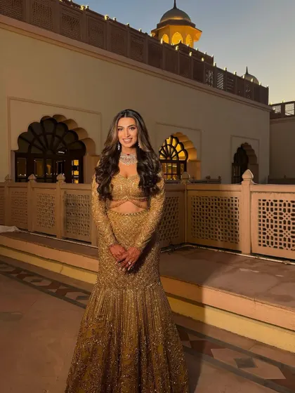 Warm golden tones lit up her Sangeet night. We paired her magnificent golden lehenga with a soft, glowing makeup look and classic Hollywood waves for a truly regal feel.