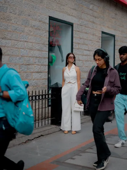 A candid shot of a model in a white outfit, captured amidst the bustle of a city street. This creates an authentic and dynamic urban fashion photo.
