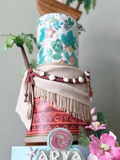 A tropical dream come true with this three-tiered Moana-themed cake. Learn to recreate the textures of her costume, craft sugar palm trees, and model her iconic boat.