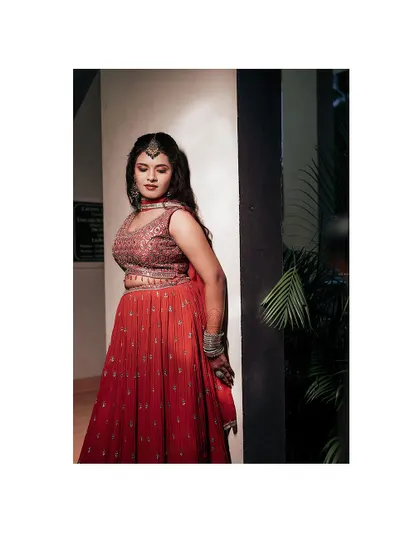 A stylish portrait of a bride in a modern red lehenga.