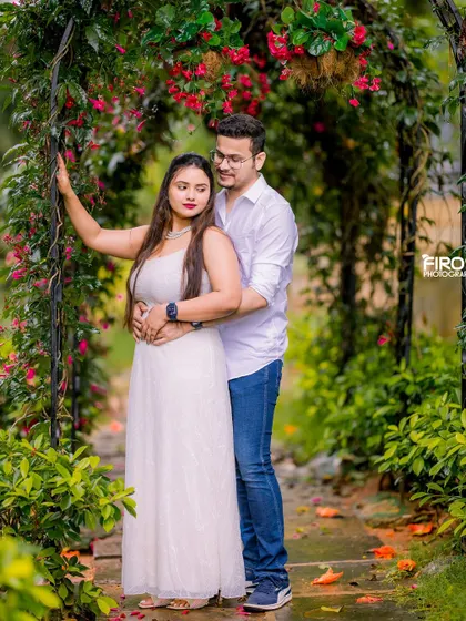 A sweet embrace under a floral archway. This portrait in simple, elegant casuals feels natural, romantic, and effortlessly beautiful.