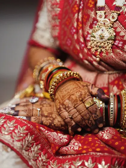 A side view of the personalized bridal mehendi, showing how the intricate patterns on the back of the hand complement the bride's beautiful bangles and wedding attire.
