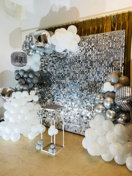 A ready-to-decorate setup with a silver shimmer wall and a white and grey balloon arrangement, perfect for a DIY party.