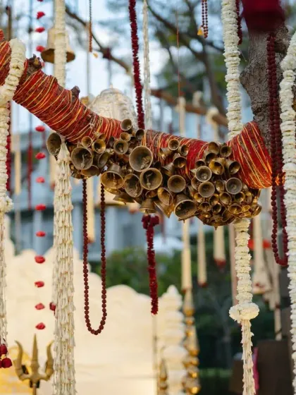A close-up of the tree decor, showing branches wrapped in sacred 'mouli' thread and adorned with clusters of brass bells. These small, authentic details are essential for creating a truly immersive themed wedding.