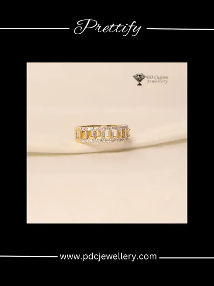 A prettifying diamond band in 18kt hallmarked gold. The design features baguette-cut diamonds channel-set between rows of round brilliant diamonds for a modern, geometric look.