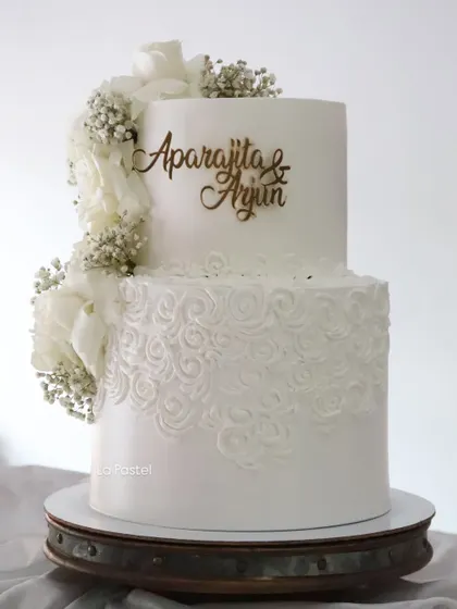 This all-white, two-tier cake is pure elegance. I used a beautiful cascading design of white sugar flowers and baby's breath on one side, with intricate rosette piping on the bottom tier for added texture.